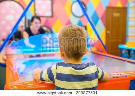 little kid plays in air hokey in Entertainment Center