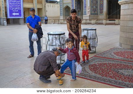 Fars Province Shiraz Iran - 19 april 2017: Shah Cheragh Shrine Fathers help their sons change their shoes after visiting the mosque for prayer.