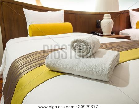 Two white laundered fluffy towels on white bed in bedroom interior at the hotel