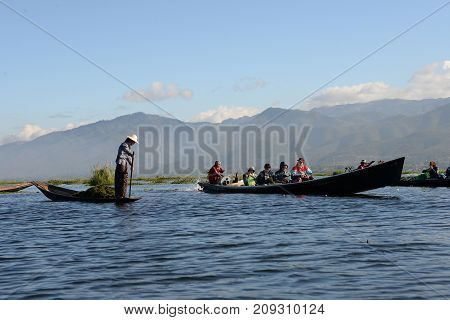Tourist take photo of Intha woman on Tradition boat transportation at Inle lake floating garden at 18 December 2016 Intha viillageInleMyanmar