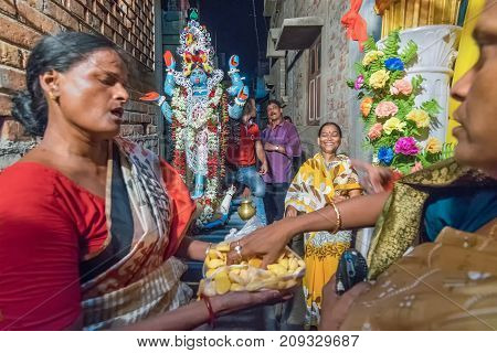 KOLKATA INDIA - JUNE 17 2017 - Female Hindu devotees worshipping Goddess Kali at night during Kali Puja Hindu festival of Deepavali or Diwali. Celebtated all over India. Shot under mixed light.