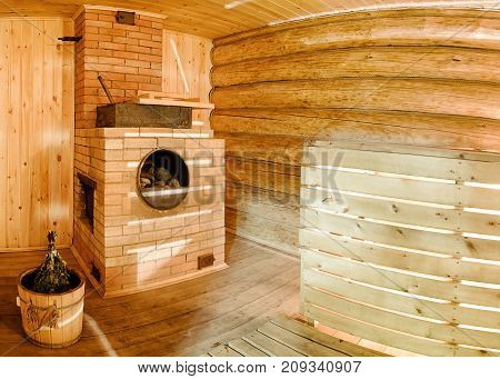 Russian wooden sauna banya with spruce broom and oven with stones.