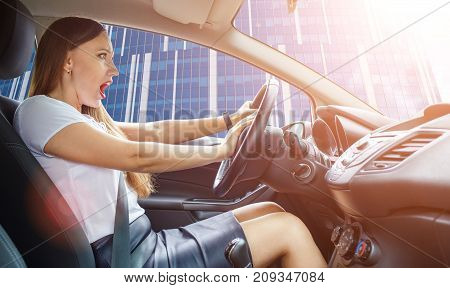 Young frightened driver woman squealing brakes in traffic jam