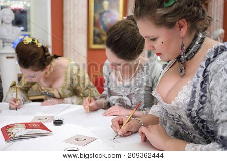 MOSCOW - SEP 16, 2017: Three women write by feathers and ink at Great Catherine Ball (dance party) in Tsaritsyno