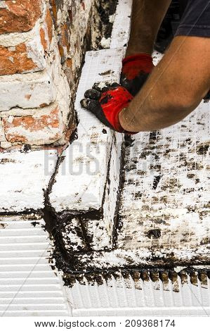 Construction worker thermally insulating house foundation walls with Styrofoam boards