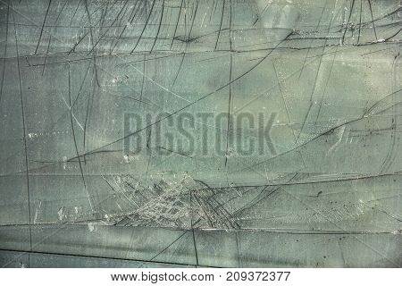 Damaged, broken glass sheet with black cracks on green background