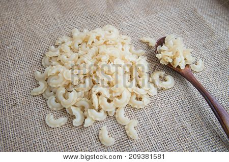 Short, curved and ruffled raw pasta on rustic background . Natural and healthy food concept. Creste di galli pasta