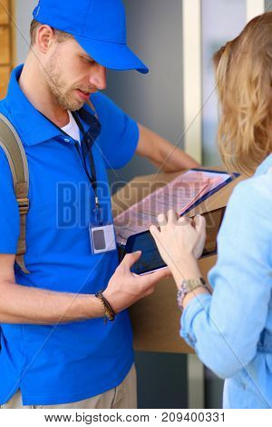 Smiling delivery man in blue uniform delivering parcel box to recipient - courier service concept. Smiling delivery man in blue uniform