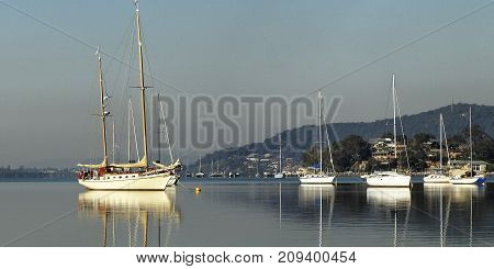 Crystal clear water reflections of beautiful & classic yachts moored in the glass smooth waters of Brisbane Water. Photographed at Gosford New South Wales Australia east coast. Photography by Geoff Childs