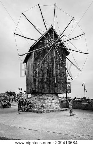 NESEBAR BULGARIA - AUGUST 21 2017: An old wooden windmill on the embankment in the old town. Black and white. Nesebar is an ancient city and one of the major seaside resorts on the Bulgarian Black Sea Coast.
