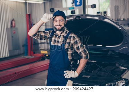 Attractive Caucasian Expert Assistant At Mechanical Work Shop, Standing, Fixing Headwear, In Special