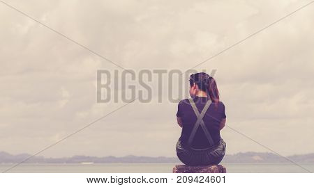 The girl sitting alone lonely at the sea. With loneliness