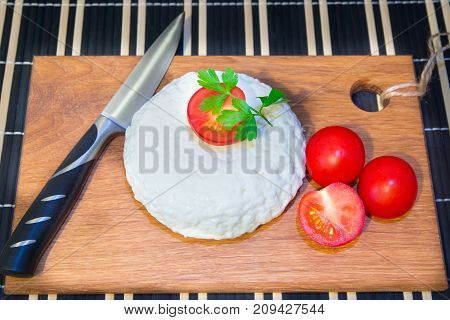 Young oak cheese cutting Board with tomatoes and parsley. Mozarella for pizzas and salads.