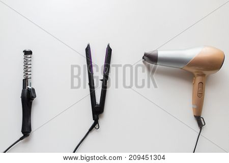 hair tools, beauty and hairdressing concept - hairdryer, hot styler and curling iron or tongs on white background