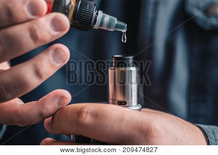 Man dripping his vape device, RDA or e-cigarette, close up, selective focus