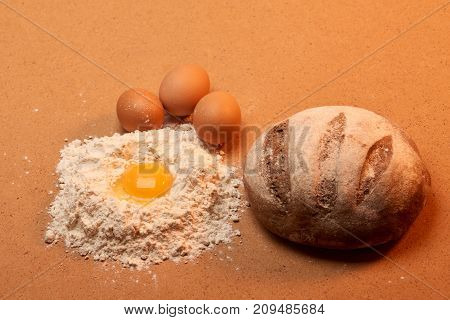 Round Bread, Three Eggs And An Egg Yolk Surrounded By Flour