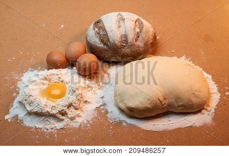 Round Bread, Three Eggs, Dough And An Egg Yolk Surrounded By Flour