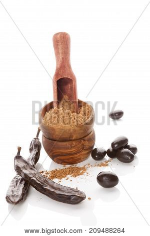 Organic carob bean pod carob powder and carob candy isolated on white background. Healthy cocoa alternative.