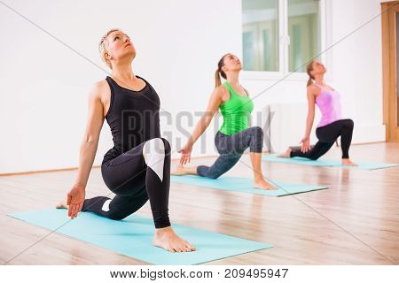 Three girls practicing yoga, Virabhadrasana / Warrior pose