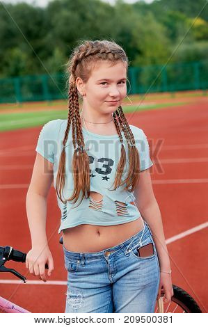 Sporty pretty teen girl loves sports.Closeup portrait of a teenage girl with a smile.outdoor stadium girl listening to music on headphones.