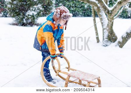 Little boy enjoying sleigh ride during snowfall. Child sledding on snow. Preschool kid riding a sledge. Child play outdoors. Kids sled in snowy winter park. Active fun for family Christmas vacation.