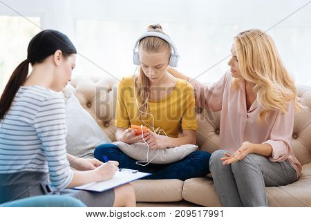 Being withdrawn. Pleasant nice adult woman talking to her daughter and trying to get a response while visiting a psychologist together with her