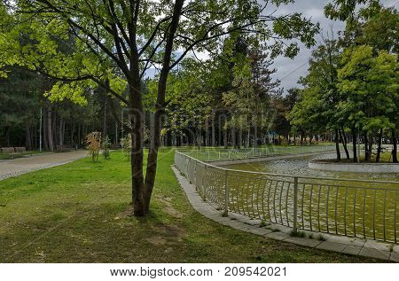 Popular  North park  for rest with autumnal old forest, wooden bench and lake in  Vrabnitsa district, Sofia, Bulgaria