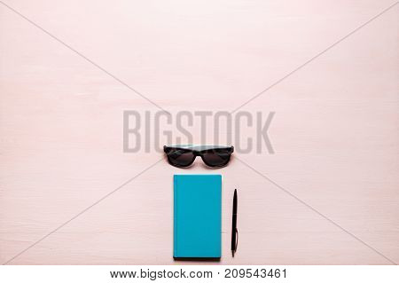 Green diary, black pen, sunglasses on pink textplace background. flat lay, top view. Feminine workspace for bloggers, designers, articles, magazines etc.