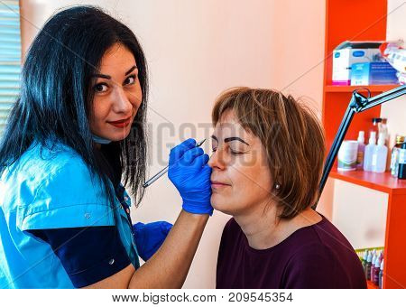Microblading in the beauty salon. Master cosmetologist at work. Eyebrow correction.