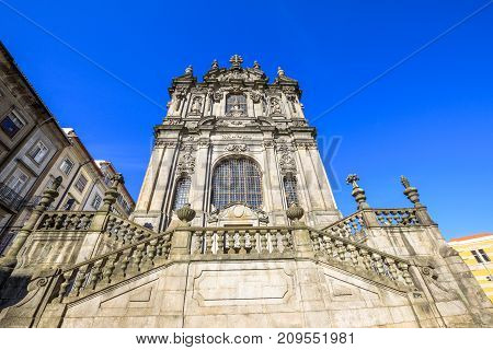 Prospective view of baroque facade of Church of Clerigos or Igreja dos Clerigos in historic center of Porto, Porgugal, one famous panoramic viewpoint of city. Sunny day in the blue sky.