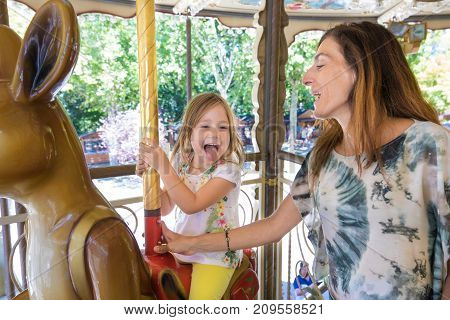 Little Girl In Carousel With Mother Sticking Her Tongue Out