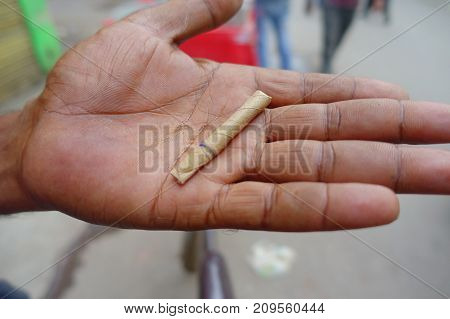 Delhi, India - September 25, 2017: Close up of a hand of a man with a leaf wrapped cigarette handmade, in the streets of Paharganj new delhi India.