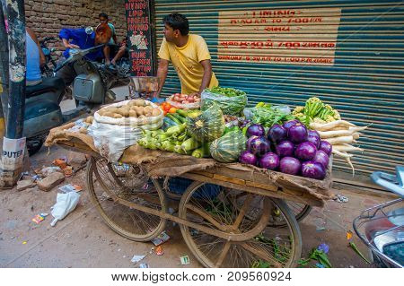 Delhi, India - September 25, 2017: Unidentified man at outdoors of a cart with vegetables, in Paharganj Delhi with muslim shoppers.