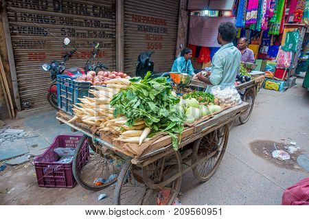 Delhi, India - September 25, 2017: Unidentified man at outdoors of a cart with vegetables, in Paharganj Delhi with muslim shoppers.