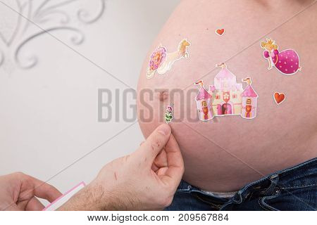Beautiful pregnant couple in love on the background. Hands of husband on the tummy of his pregnant wife. Young man tenderly stroked pregnant belly of his wife. Husband kissing pregnant belly.