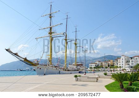 TIVAT MONTENEGRO - SEPTEMBER 10 2017: Sailboat near seafront of Tivat Montenegro. Unidentified people are strolling along promenade