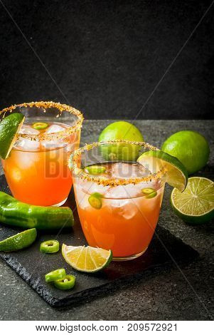 Alcohol. Traditional Mexican South American cocktail. Spicy michelada with hot jalapeno peppers and lime. On a dark stone table. Copy space
