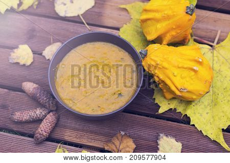 Pumpkin fricassee.Pumpkin soup in a little brown bowl on a wooden background. Autumn time. Leaves and pumpkins
