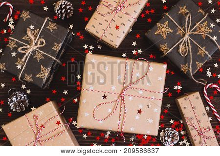 Christmas holiday gift box on decorated festive table with pine cones and sparkle stars on wooden background. Packaging gift wrap and ribbons twine. Winter time new year