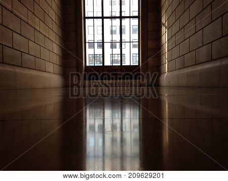 An erie and lonely, yet bright hallway  showcasing a beautiful arched window.