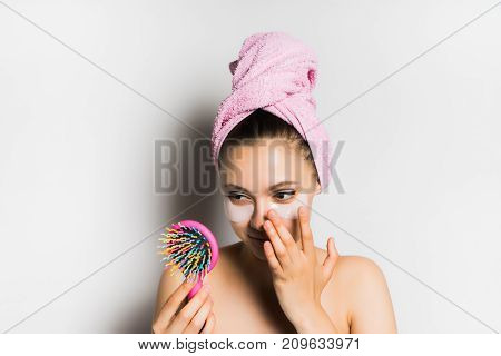 the girl after the shower puts patches on the face and looks in the mirror on her hairbrush, isolated