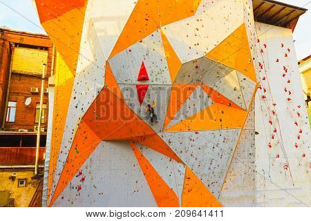 The young woman on rock wall in sport center outdoor