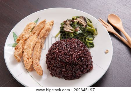 Vegetarian food Thai-style with Stir-fried vegetables spinac and shiitake Riceberry rice tamarind paste and sour soup (Selective Focus Focus on the Riceberry rice)