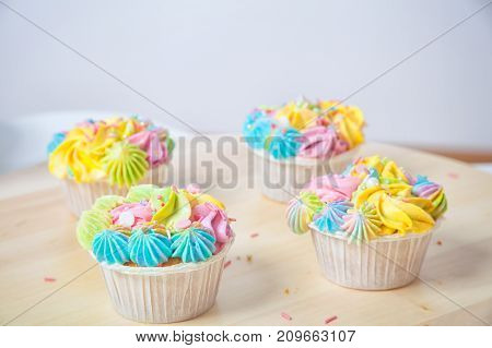 Homemade cupcake with cream and berries decorated with delicious cream and colorful decorations stand in a row on a white table