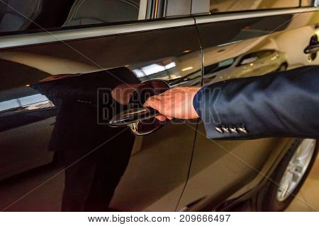 Male hand holding silver doorhandle a white car