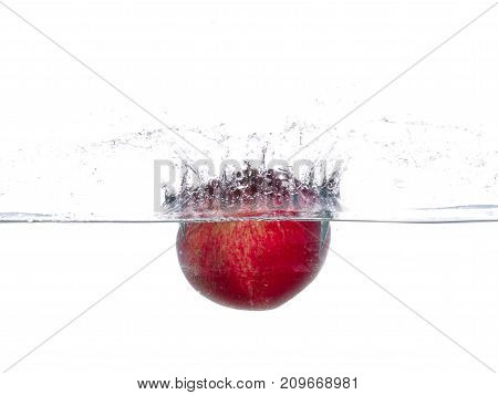 Red, green and ripe garnet falls into the water. Water splashes. Isolated picture on white background