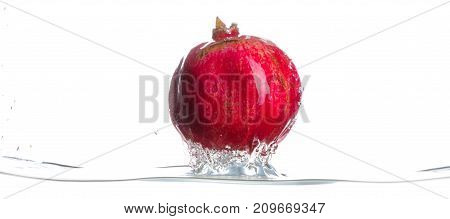 Red, whole and ripe garnet came from water. Water splashes. Isolated picture on white background