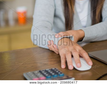Closeup woman holding her wrist pain from using computer long time. Office syndrome concept.