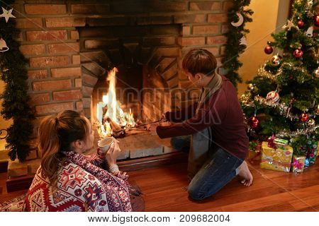 Young couple spending Christmas night at firepalce at home