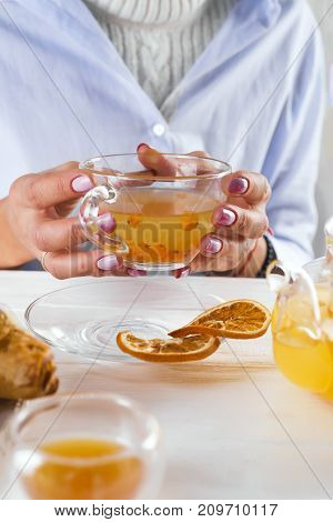 famele hands holding hot cup of sea-buckthorn tea.breakfast with croissants and honey